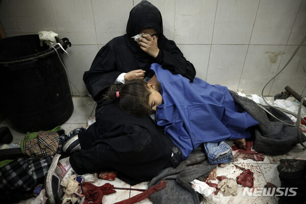 지난달 22일(현지시간) 가자지구 남부 칸유니스의 나세르 병원에서 팔레스타인 여성이 이스라엘의 가자지구 공습으로 부상을 입은 딸 옆에 앉아 울고 있다. (출처: 뉴시스)