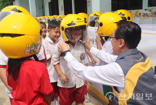 안전모 전달식에 참여한 KB손해보험 조정래 인니법인장이 Sinar Cahaya Kasih 학교 학생들에게 안전모를 씌워주고 있다. (제공: KB손해보험) ⓒ천지일보 2024.02.19.