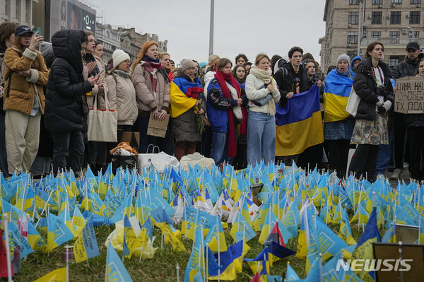 24일(현지시간) 우크라이나 키이우 중심부의 마이단 광장 근처에 있는 전쟁 사망자를 위한 추모비에 주민들이 모여 있다. (출처: 뉴시스)