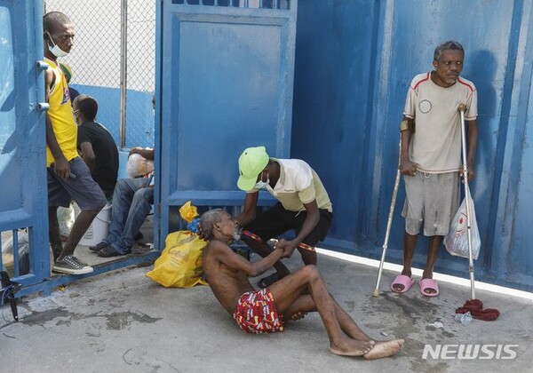 [ 포르토프랭스=AP/뉴시스] 아이티 수도 포르토프랭스의 국립교도소에서 3월 3일 무장 갱단의 습격으로 수백명이 탈옥한 뒤 남은 노약자 수감인들 끼리 응급 치료를 하며 서로를 돌보고 있다. 2024.03. 04.