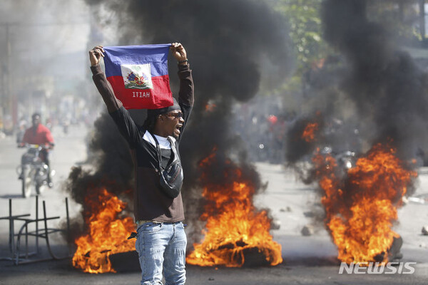 아이티의 미래는 어디로 갈까. 1일(현지시간) 아이티 포르토프랭스에서 한 시위대가 아리엘 앙리 총리의 사임을 요구하는 시위를 벌이며 아이티 국기를 들고 있다. (출처: 뉴시스)