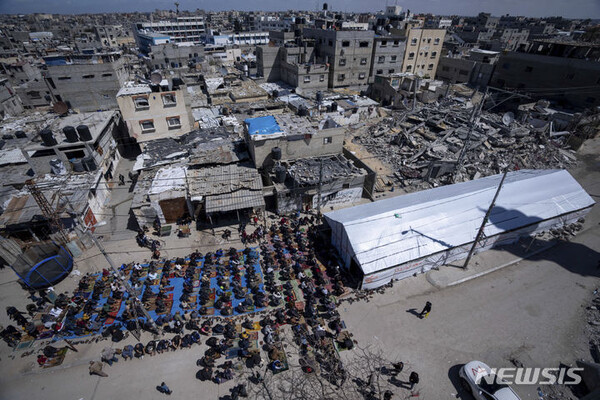 15일(현지시간) 팔레스타인인들이 가자지구 라파에서 이스라엘 공습으로 파괴된 모스크 폐허 근처에서 라마단 첫 번째 금요일 기도를 하고 있다. (출처: 뉴시스)