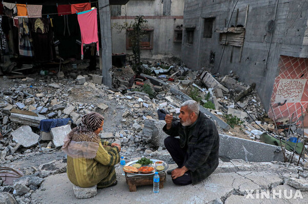 13일(현지시간) 가자지구 중심 도시 데이르 엘 발라에 있는 집 잔해 위에서 팔레스타인인들이 일몰시간 이후 금식을 깨고 식사를 하고 있다. (출처: 뉴시스)