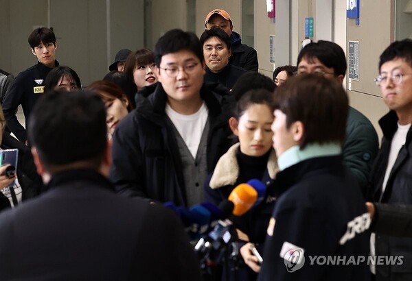 황대헌(왼쪽 뒷쪽) 이 19일 인천국제공항을 통해 입국 후 인터뷰를 하고 있는 박지원을 바라보고 있다. (출처: 연합뉴스)