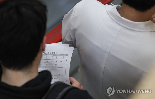 20일 대구 한 대학병원에서 의대생이 휴학 신청서 여러 장을 들고 의사 선배를 따라가고 있다. (출처: 연합뉴스)