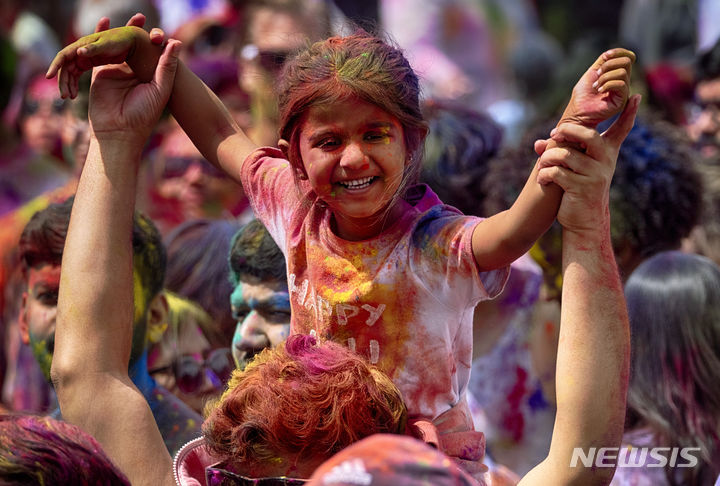 이날 미국 로스앤젤레스 엔시노 지역에서 홀리를 기념하는 한 힌두교 신도의 어깨 위에서 색색의 가루를 바른 어린 소녀가 춤을 추고 있다. (출처: 뉴시스)