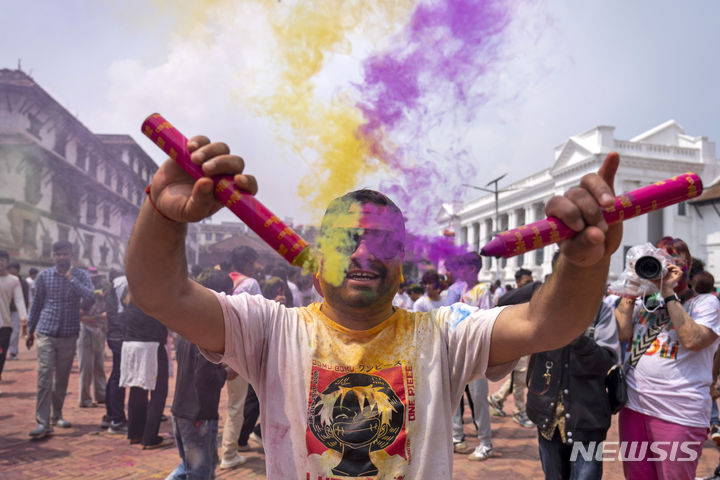 24일(현지시간) 네팔 카트만두에서 한 남성이 힌두교의 색채 축제인 홀리를 기념하는 행사에서 색 연기를 피우고 있다. (출처: 뉴시스)