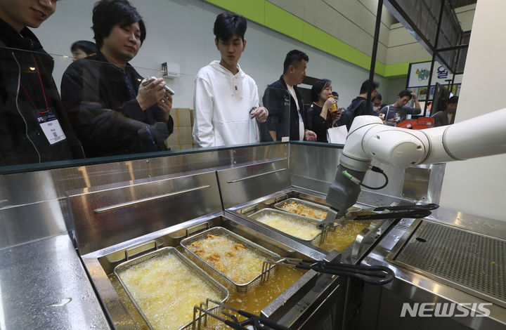 서울 강남구 코엑스에서 열린 IFS 프랜차이즈 창업 박람회에서 관람객들이 치킨 프랜차이즈 부스에서 튀김기계를 살펴보고 있다.