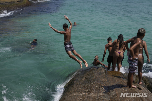 3월 20일(현지시간) 폭염이 들끓는 브라질 리우데자네이루 아르포아도르 해변의 바위에서 한 젊은이가 바다로 뛰어내리고 있다. (출처: 뉴시스)