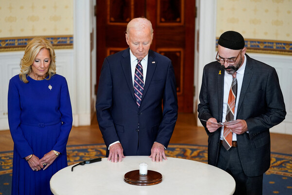 U.S. President Joe Biden, flanked by first lady Jill Biden and Rabbi Aaron Alexander of Adas Israel Congregation, participate in a candle lighting event to mark the anniversary of the Oct. 7 Hamas attacks on Israel, at the White House in Washington, U.S., October 7, 2024. REUTERS/Nathan Howard