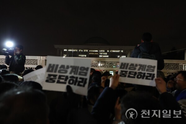 [천지일보=박준성 기자] 윤석열 대통령이 3일 비상 계엄을 선포한 가운데 국회로 몰려든 시민들이 ‘비상계엄 중단하라’라는 문구가 적힌 피켓을 들고 있다. ⓒ천지일보 2024.12.04.