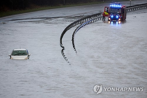 1일(현지시간) 영국 브램홀 인근 A555 도로에서 소방관들이 홍수에 갇힌 한 남성을 차에서 구출하고 있다. (출처: 연합뉴스)