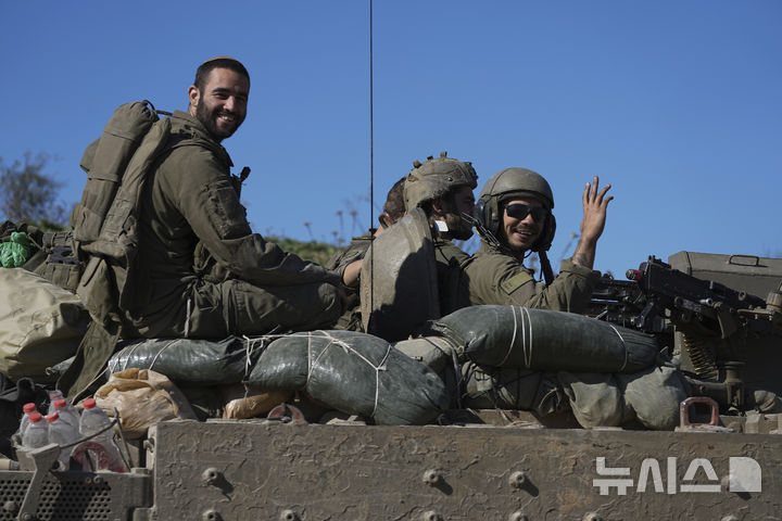 18일(현지시간) 가자지구에서 이스라엘로 건너가는 이스라엘 군인들이 APC에서 카메라를 향해 손을 흔들고 있다. (출처: 뉴시스)