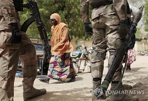 나이지리아 보르노 주 인근의 그와자의 검문소에서 한 여성이 군인들 앞을 지나가고 있는 모습. 이 지역은 지난 2015년 보코하람에 장악됐다가 해방됐다. (출처:연합/ AP)