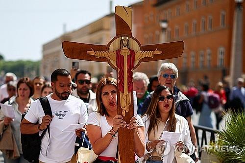 (로마 로이터=연합뉴스) 한 여신도가 21일(현지시간) 교황의 선종 소식을 들은 뒤 대형 십자가를 들고 성베드로 광장 근처를 행진하고 있다. 2025.04.21.