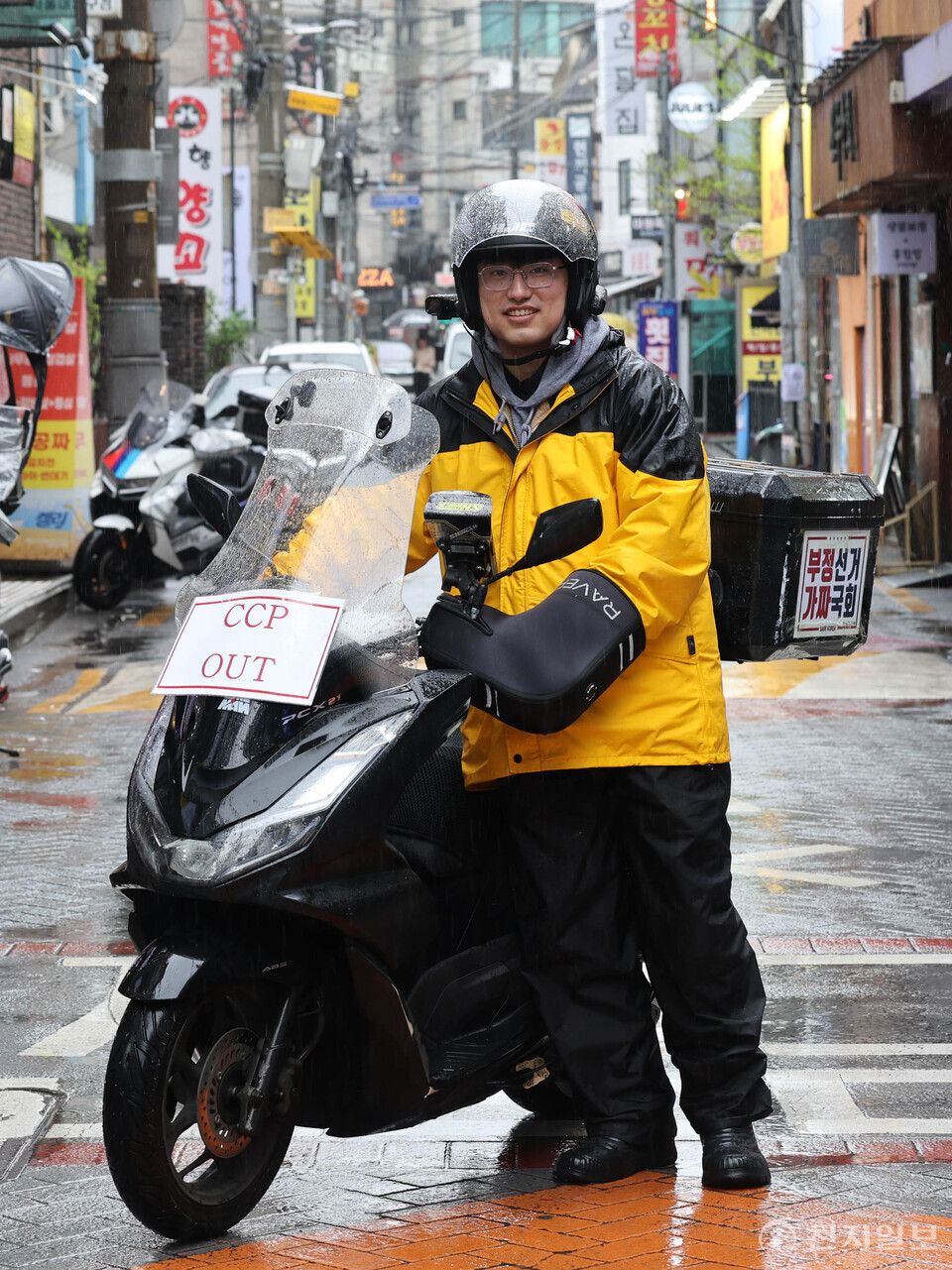 [천지일보=남승우 기자] 배달라이더 허지웅(27)씨가 서울 관악구 샤로수길에서 오토바이와 함께 서 있다. 그의 헬멧과 배달통에는 ‘CCP OUT(중국공산당 아웃)’ ‘부정선거 가짜 국회’ 등 팻말이 붙어 있다. ⓒ천지일보 2025.05.01.