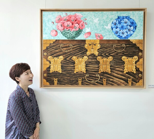 청주공업고등학교에 재직 중인 이종은 교사가 자신이 기증한 그림 옆에 서서 작품을 바라보고 있다. (제공: 충청북도교육청)