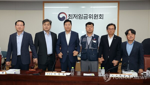 이인재 최저임금위원장(왼쪽 두 번째)이 10일 정부세종청사에서 열린 제12차 전원회의에서 내년 최저임금을 시간당 1만 320원으로 17년 만에 합의로 결정한 뒤 공익위원-사용자위원-근로자위원과 손을 잡고 있다. (출처: 연합뉴스)