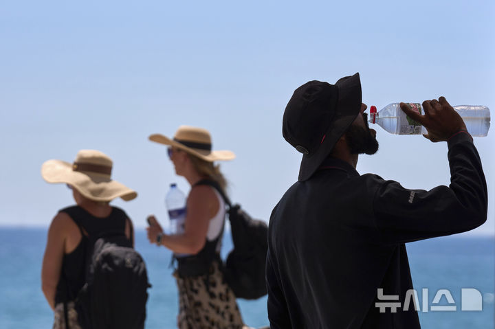 지난 2일(현지시간) 스페인 바르셀로나 해변에서 더운 날씨에 한 관광객이 물을 마시고 있다. (출처: 뉴시스)