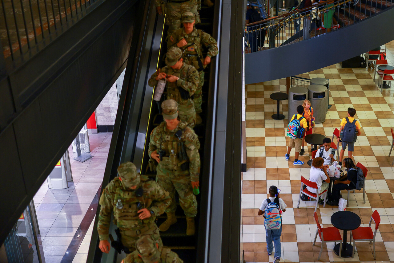 지난 25일 미국 워싱턴 D.C.에서 개학철을 맞아 학생들이 식사를 하는 동안 권총을 휴대한 루이지애나 주방위군 대원들이 순찰을 돌고 있다. 이는 도널드 트럼프 미국 대통령이 범죄 예방을 돕기 위해 수도 전역에 주방위군과 법 집행 인력을 배치하라고 명령한 지 몇 주 뒤의 모습이다. (출처: REUTERS/Jose Luis Gonzalez, 연합뉴스)