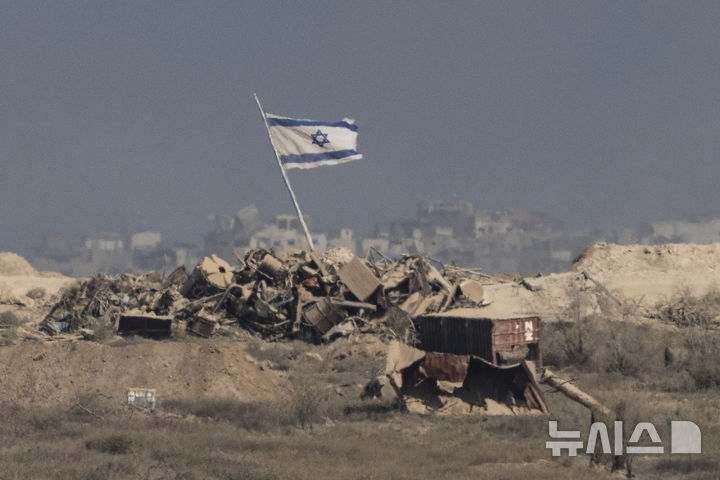 26일(현지시간) 공습을 받은 가자지구의 잔해 위로 이스라엘 국기가 펄럭이고 있다. (출처: 뉴시스)