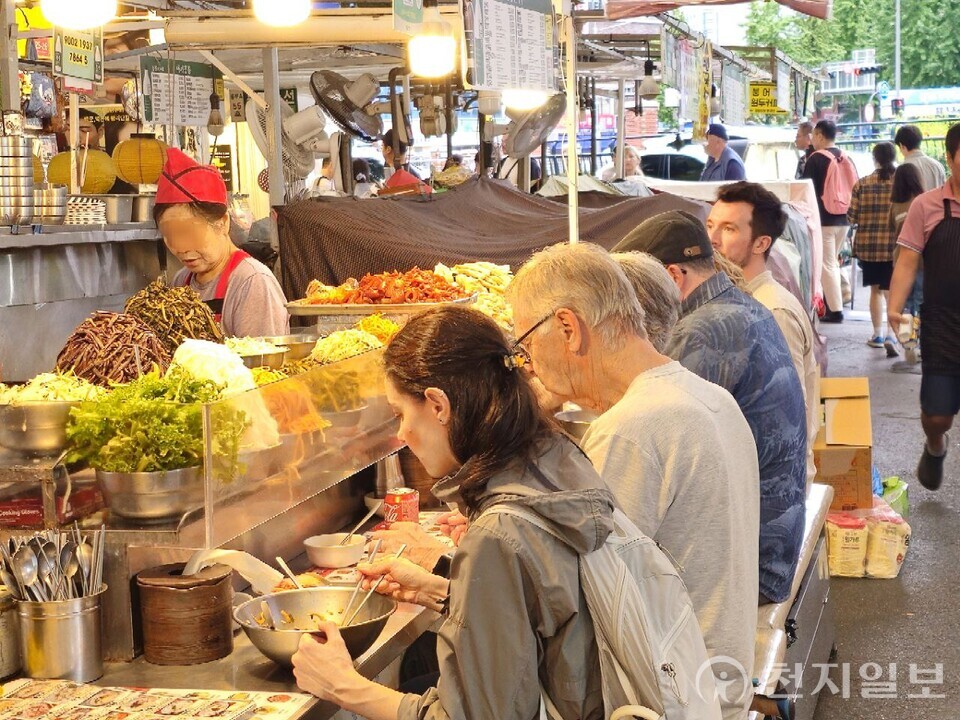 [천지일보=양효선 기자] 추석 전날인 5일 오후 서울 종로구 광장시장에서 다양한 나물과 전통 반찬을 즐기려는 손님들이 길게 늘어선 가운데, 외국인 관광객들도 현지 식문화를 체험하며 식사를 즐기고 있다. ⓒ천지일보 2025.10.05.