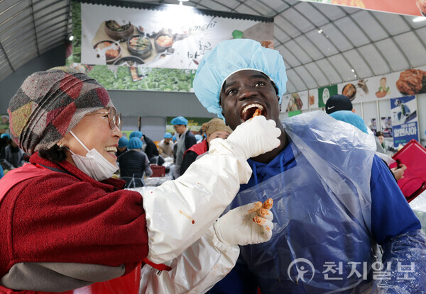 지난해 평창고랭지김장축제장을 방문한 외국인이 자원봉사자로부터 잘 버무려진 김장 김치를 받아 먹으며 즐거워하고 있다. (제공: 평창고랭지김장축제위원회) ⓒ천지일보 2025.10.29.