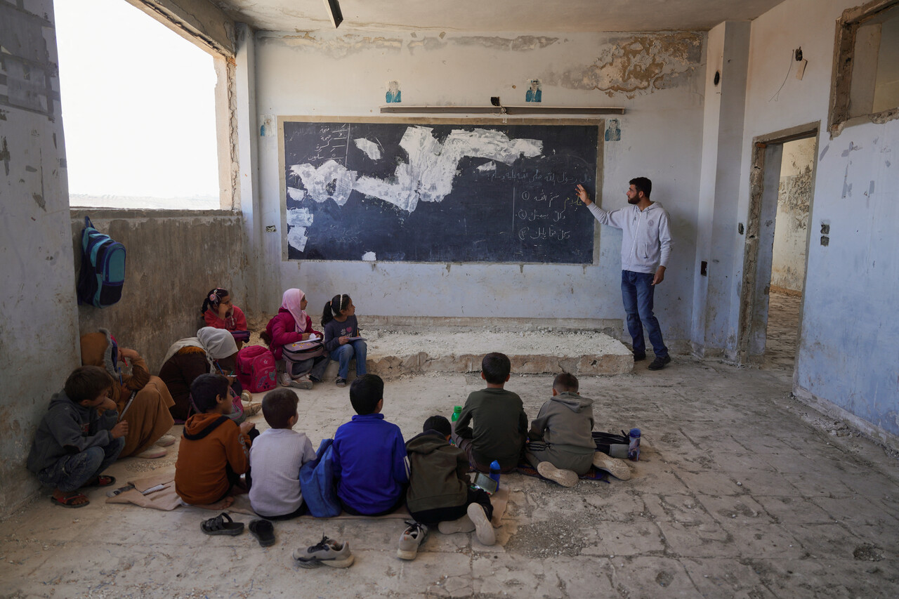 이날 시리아 이들리브 교외 하빗에 있는 알리살라 학교의 파손된 교실 안에서 한 교사가 바닥에 앉은 학생들에게 수업 내용을 설명하고 있다. (REUTERS/Karam al-Masri, 연합뉴스)