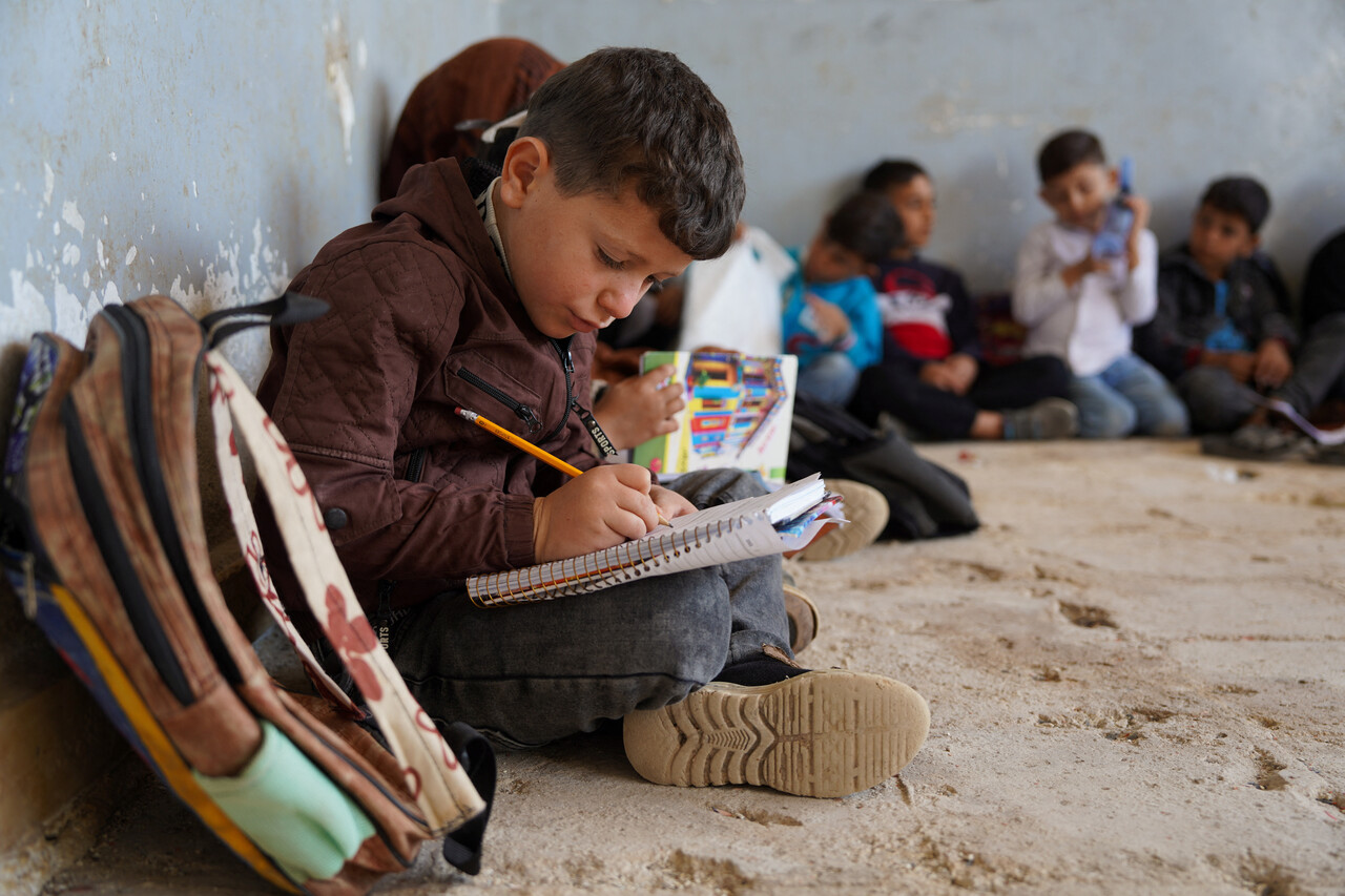 이날 알리살라 학교의 책상이 없는 교실 바닥에 앉아 한 학생이 공책에 글을 쓰고 있다. (REUTERS/Karam al-Masri, 연합뉴스)