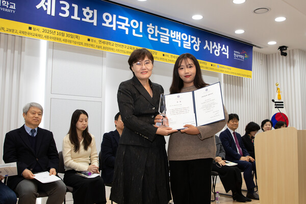 31회 외국인 한글백일장에서 장원으로 선정된 마스 데위 까니아 시티 씨(오른쪽)가 이희경 연세대학교 한국어학당 부원장(교육대학원 교수)으로부터 연세대학교 총장상과 트로피를 받고 있다. (제공: 연세대학교)