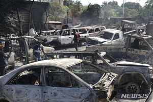 지난달 26일 아이티 포르토프랭스에서 무장 갱단의 폭력 사태로 정비소에 불이 난 가운데 주민들이 회수할만한 부품을 찾고 있다. 현재 무정부상태에 놓인 아이티는 치안 혼란이 갈수록 악화하고 있다. (출처: 뉴시스)